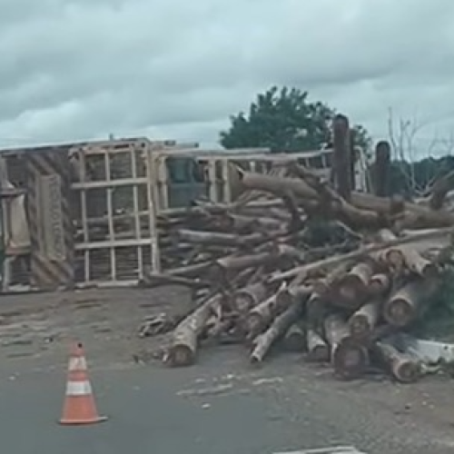 Carreta tomba na rotatória de acesso ao shopping e espalha carga de madeira na rodovia